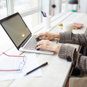 Picture of hands working on a laptop sitting on desk 