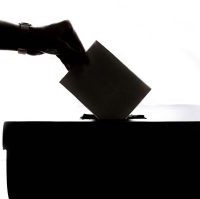 Picture of hand casting a paper-based vote into a box