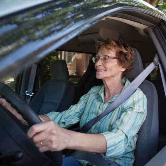 Older smiling woman driving car