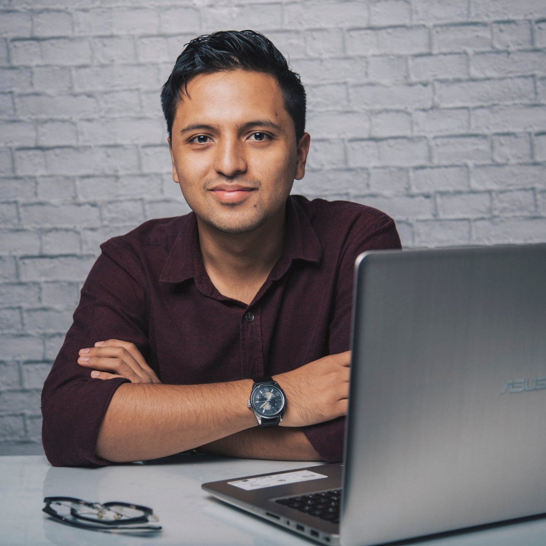 Picture of man sitting at desk with laptop and glasses