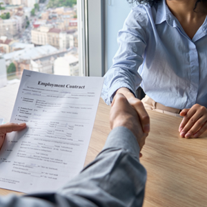 Picture of man with Employment Contract in one hand and shaking hands with woman