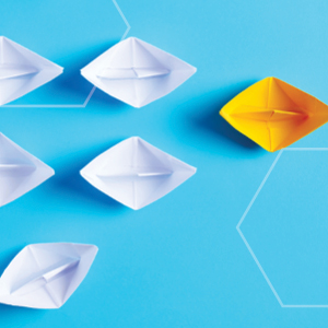 Picture of white paper boats following a yellow paper boat