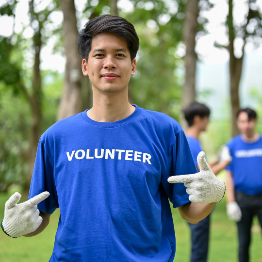 Man standing in woods wearing shirt that has the word Volunteer on it